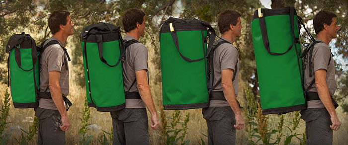 Das Bild zeigt die unterschiedlichen Größen des Haulbag Herstellers Metolius. Vor einem waldigen Hintergrund sieht man immer den selben MAnn mit je einem verschieden großen, grünen Haulbag. Es sind vier unterschiedlich große verschiedene Modelle zu sehen.